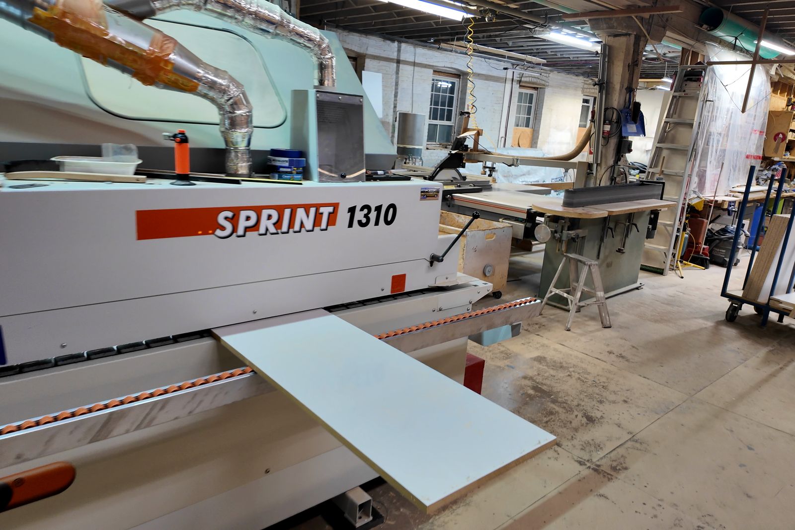Edge bander with a finished white panel in the workshop